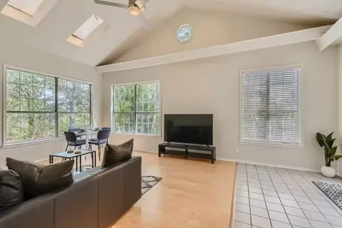 a living room with furniture a flat screen tv and a floor to ceiling window