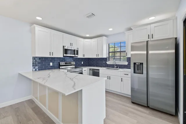 a kitchen with stainless steel appliances granite countertop a refrigerator a stove a sink and a microwave