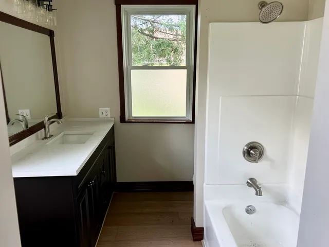 a bathroom with a tub sink and mirror