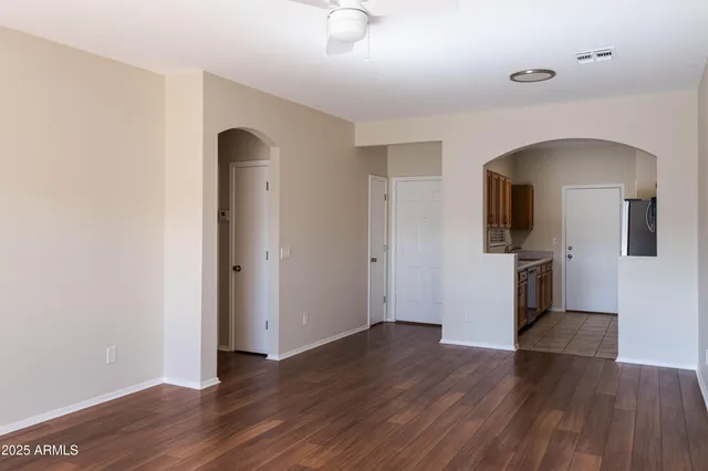 an empty room with wooden floor and a ceiling fan