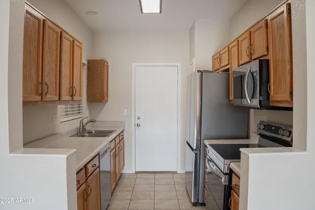 a kitchen with stainless steel appliances granite countertop a refrigerator a stove and a sink