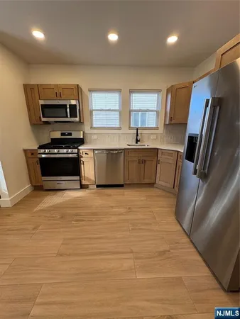 a large kitchen with stainless steel appliances a stove a sink a microwave a refrigerator a sink and a refrigerator