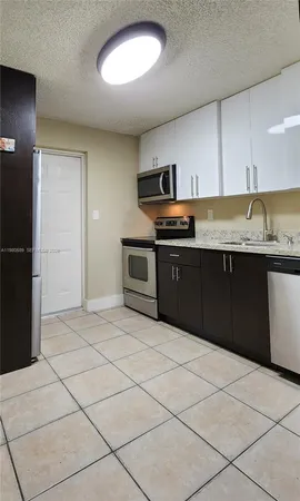 a large kitchen with stainless steel appliances granite countertop a stove top oven a sink and a refrigerator