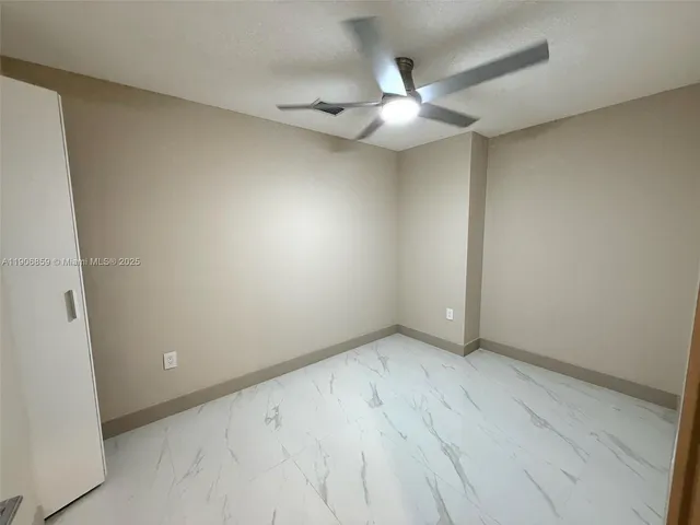 an empty room with a chandelier fan and a table