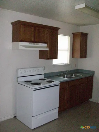 a kitchen with granite countertop a sink stove and microwave