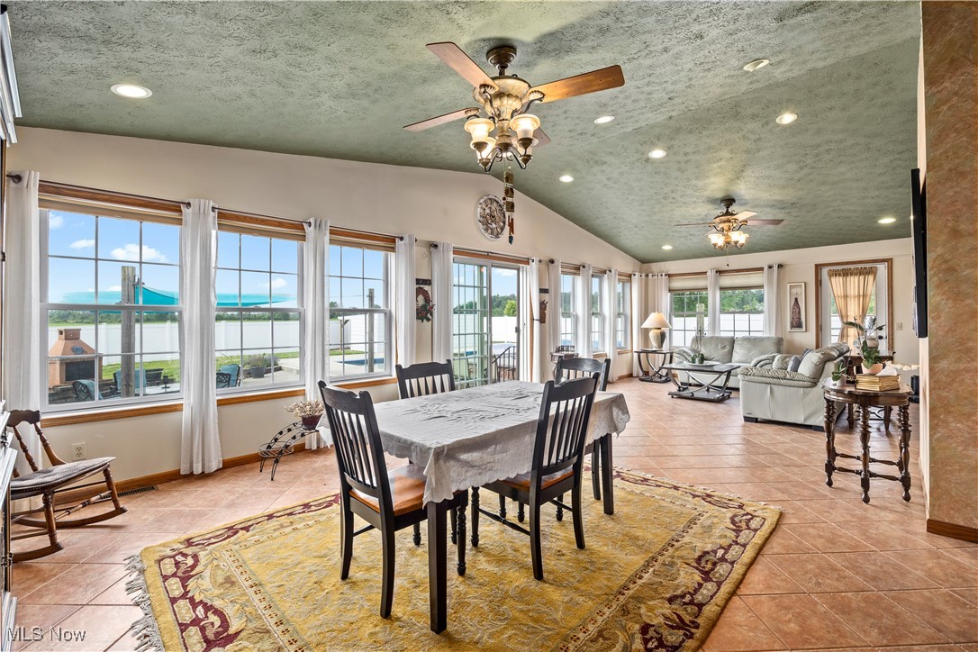 47147 Merriam Road Wellington, OH 44090 - Photo 6 of 49 Dining area with ceiling fan, vaulted ceiling, light tile patterned flooring, recessed lighting, and a water view