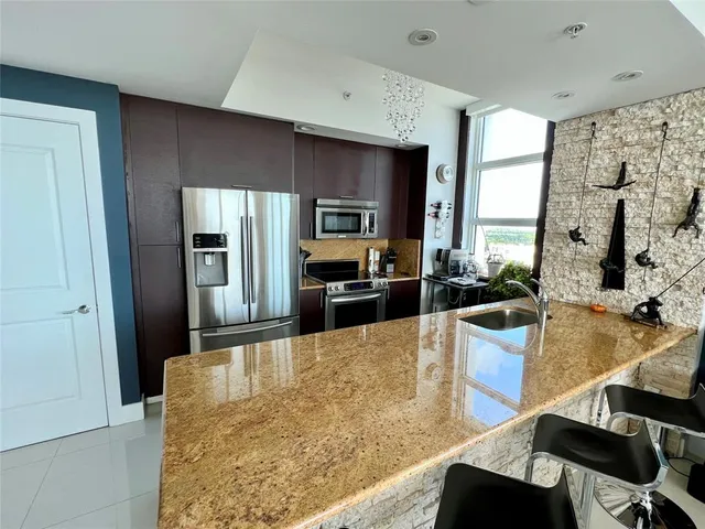 a large kitchen with kitchen island a large counter top stainless steel appliances and cabinets
