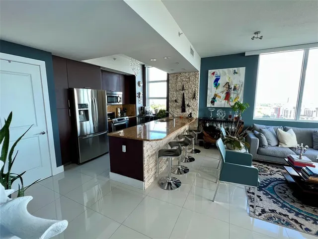 a living room with furniture large window and stainless steel appliances