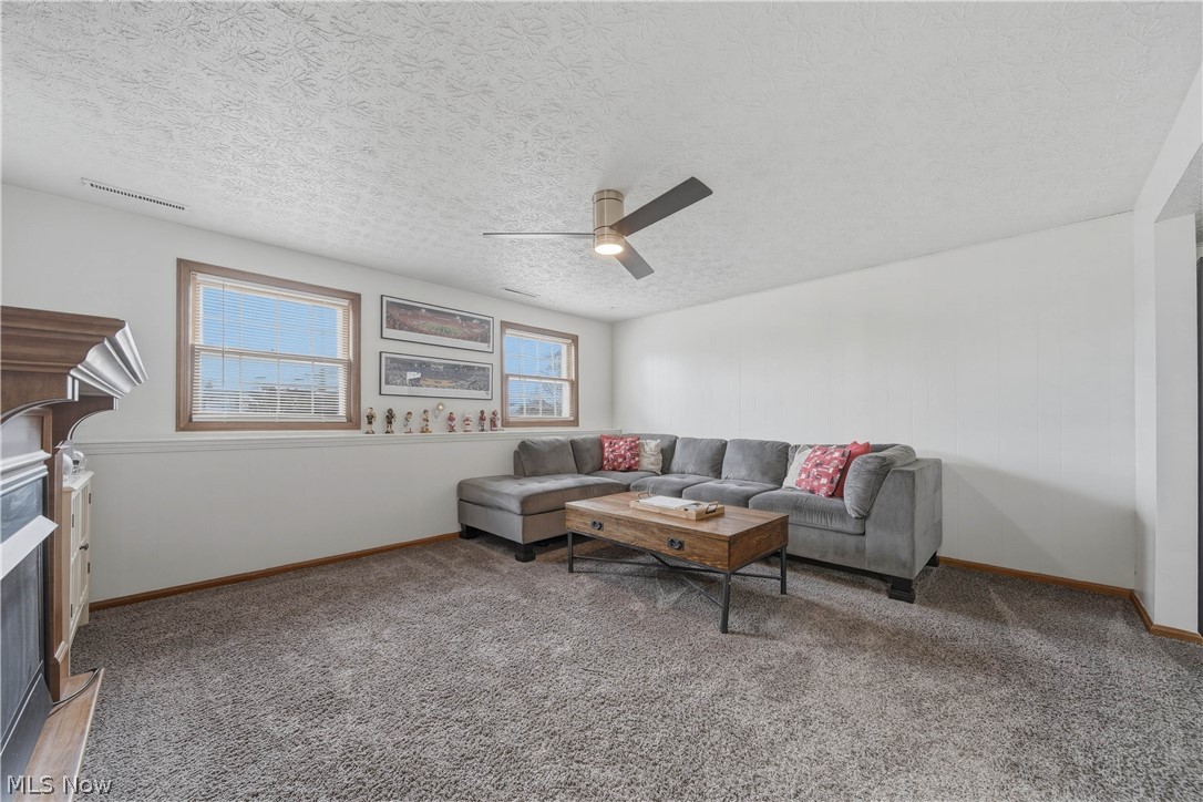702 Perry Drive Northwest Canton, OH 44708 - Photo 27 of 46 Living area featuring ceiling fan, light colored carpet, a textured ceiling, and a fireplace