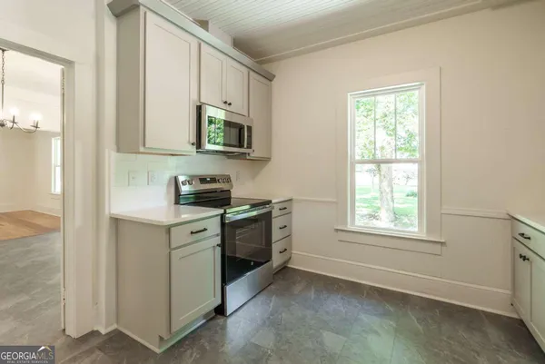 a kitchen with stainless steel appliances granite countertop white cabinets and window