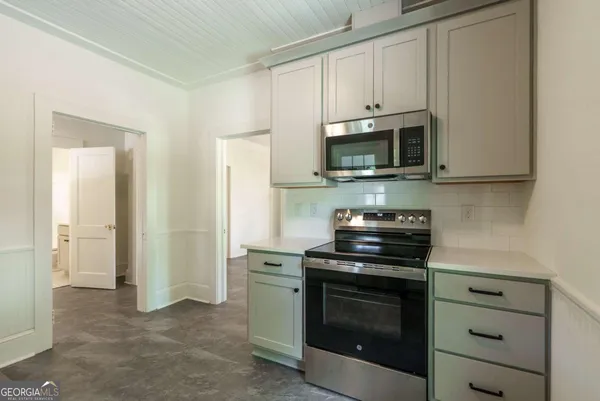 a kitchen with stainless steel appliances granite countertop white cabinets and a stove top oven