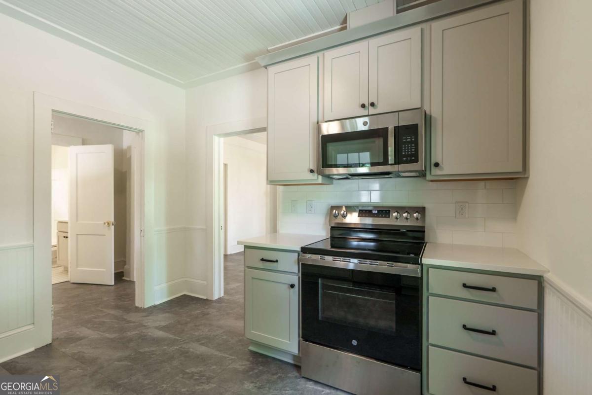 5380 Guthrie Road Loganville, GA 30052 - Photo 15 of 38 a kitchen with stainless steel appliances granite countertop white cabinets and a stove top oven