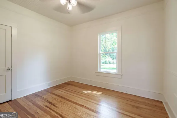 a view of empty room with wooden floor and fan