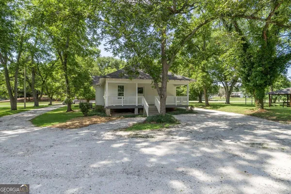 a front view of a house with a garden and trees