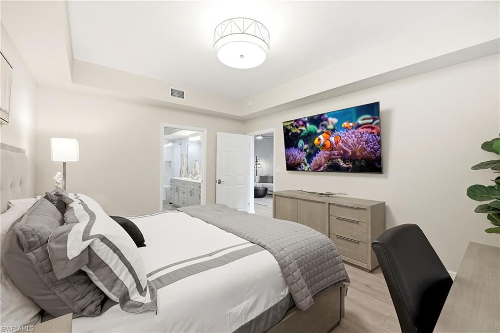 401 Bayfront Place, Unit 3307 Naples, FL 34102 - Photo 14 of 28 Bedroom featuring a raised ceiling, light wood-style flooring, and ensuite bathroom