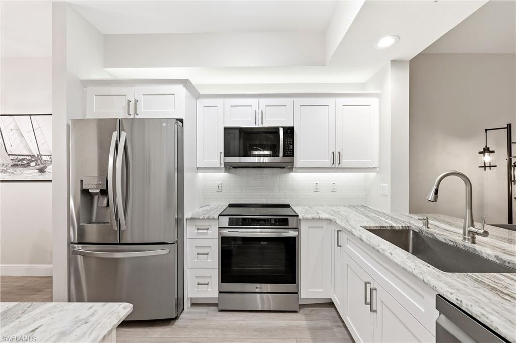401 Bayfront Place, Unit 3307 Naples, FL 34102 - Photo 5 of 28 Kitchen featuring stainless steel appliances, light stone counters, and white cabinetry