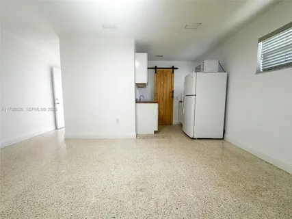 a view of a storage & utility room with a fridge