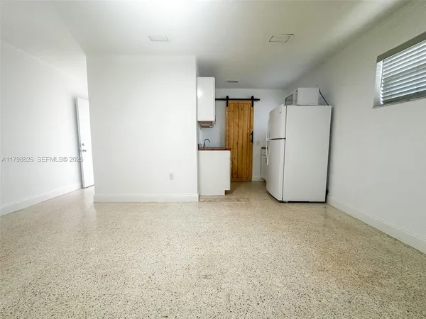 a view of a storage & utility room with a fridge