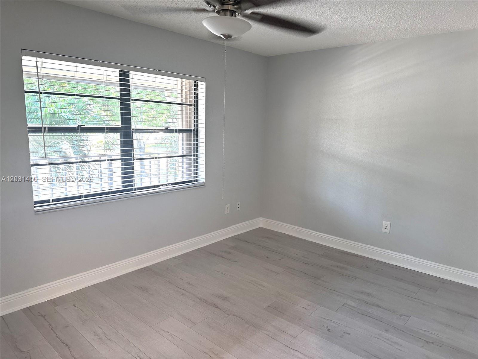 23398 Lyons Road, Unit 309 Boca Raton, FL 33428 - Photo 10 of 16 a view of an empty room with wooden floor and a window