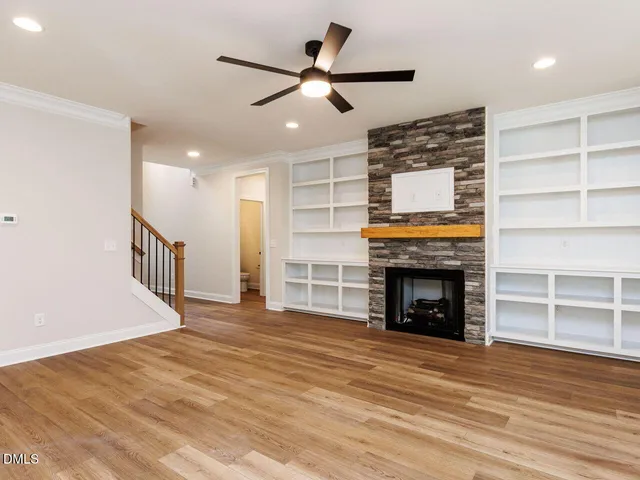 a view of an empty room with wooden floor fireplace and a window