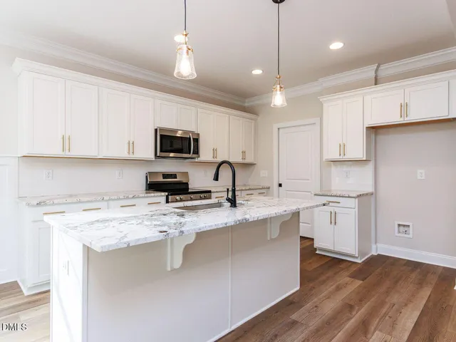 a kitchen with kitchen island granite countertop stainless steel appliances and white cabinets