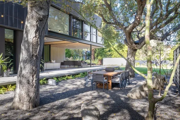 a view of backyard with table and chairs and a large tree