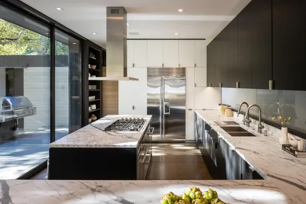 a kitchen with stainless steel appliances kitchen island granite countertop a sink counter space and a stove top oven