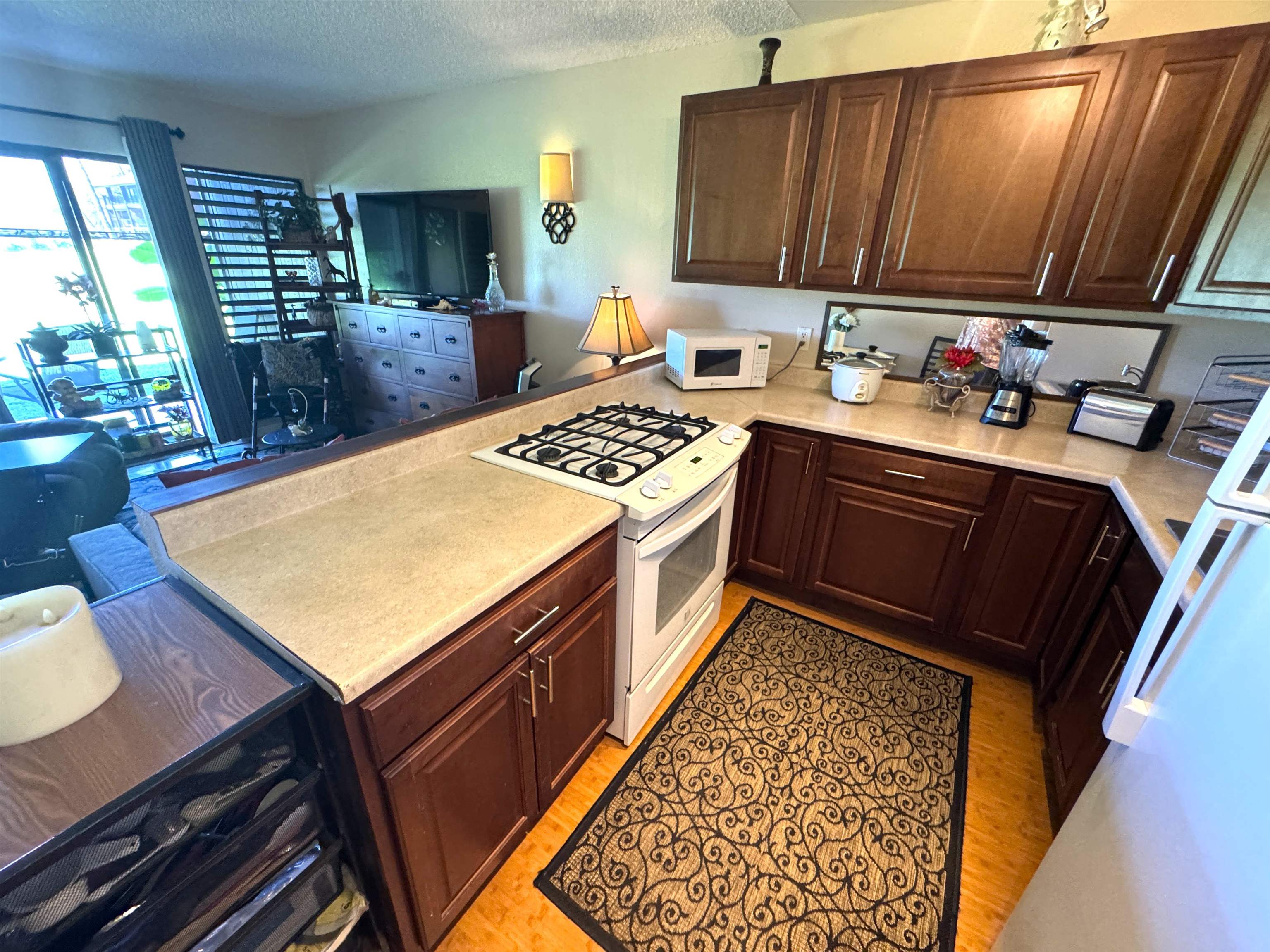 Kamehameha V Highway, Unit 123B Kaunakakai, HI 96748 - Photo 15 of 25 a kitchen with a stove a sink a refrigerator wooden floor and a dining table
