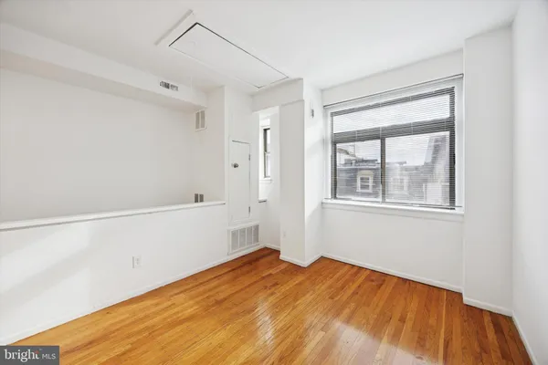 a view of empty room with wooden floor and fan