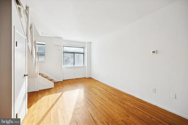 an empty room with wooden floor and windows