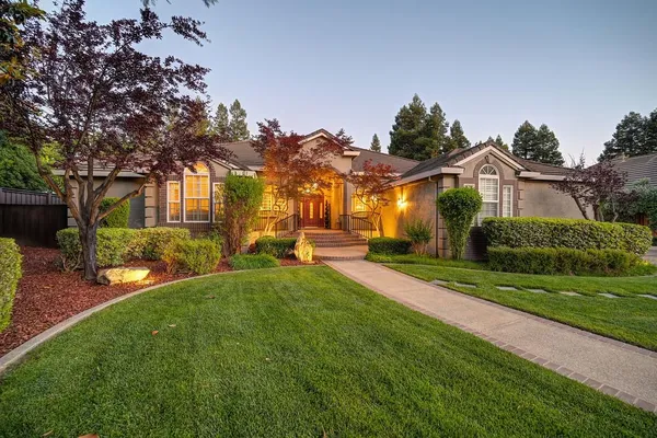 a view of a house with a big yard plants and large trees