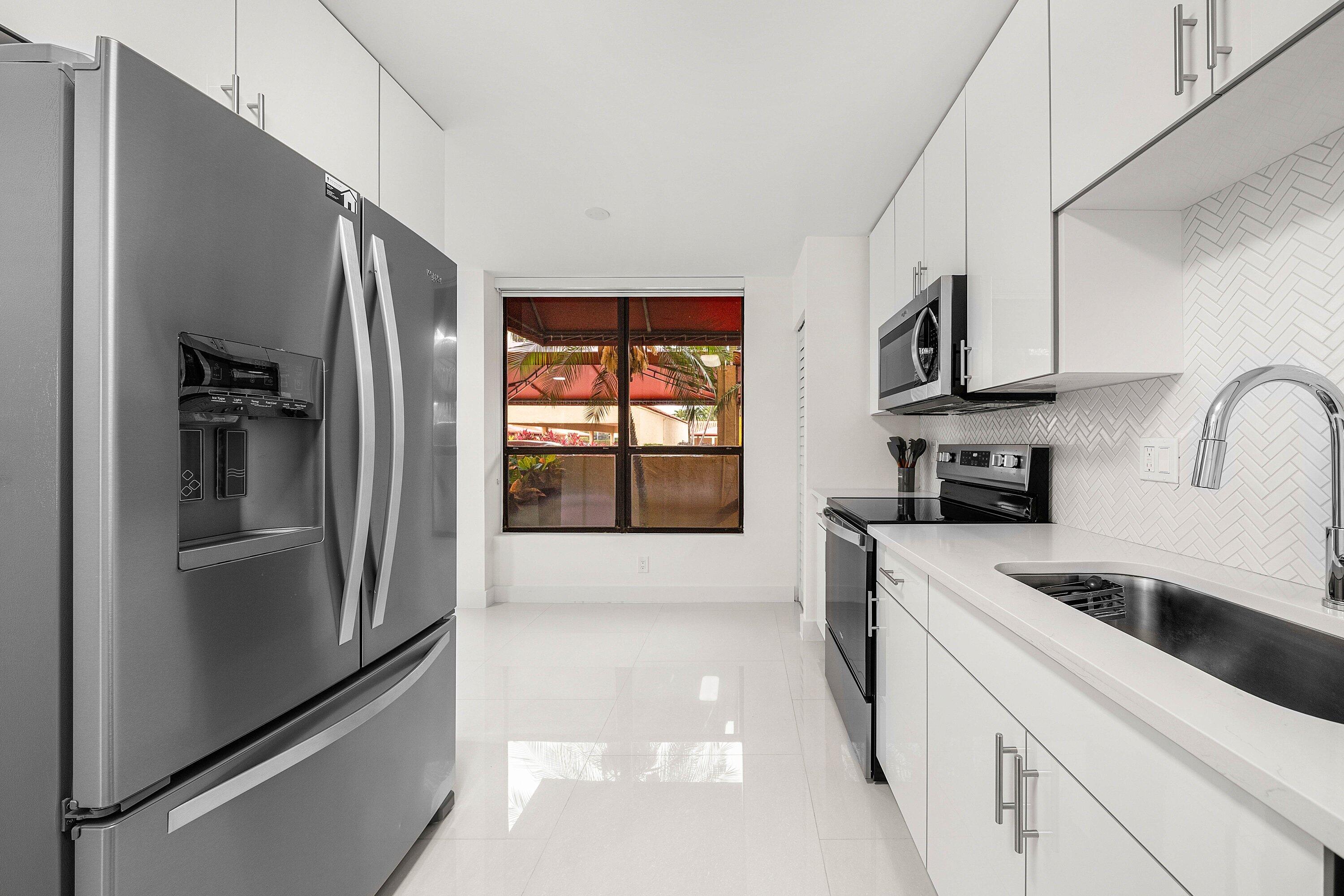 7145 Promenade Drive, Unit 101 Boca Raton, FL 33433 - Photo 14 of 35 a kitchen with stainless steel appliances granite countertop a refrigerator and a stove