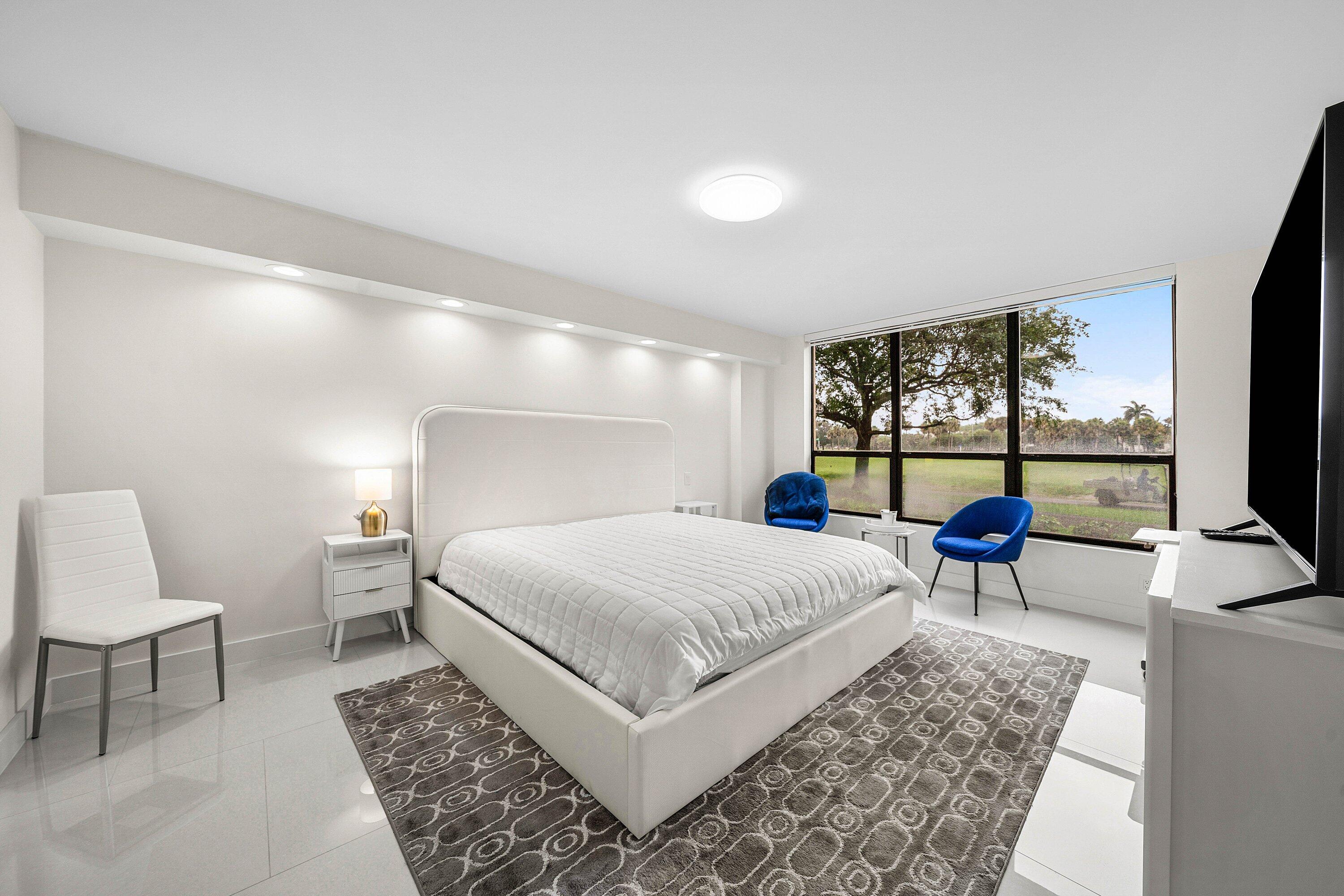7145 Promenade Drive, Unit 101 Boca Raton, FL 33433 - Photo 17 of 35 a bedroom with a large bed a flat screen tv and windows