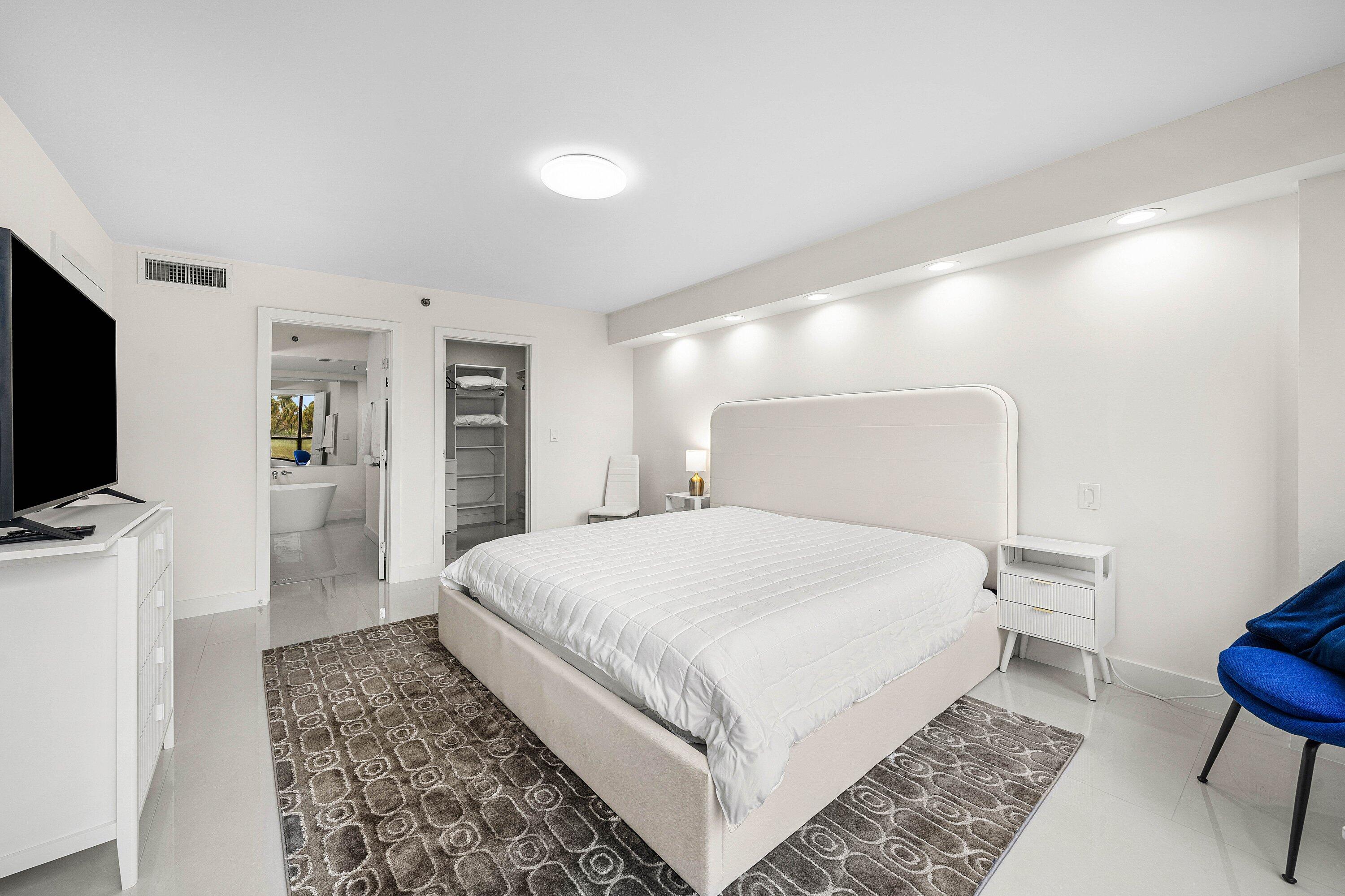 7145 Promenade Drive, Unit 101 Boca Raton, FL 33433 - Photo 19 of 35 a bedroom with a bed and a flat screen tv
