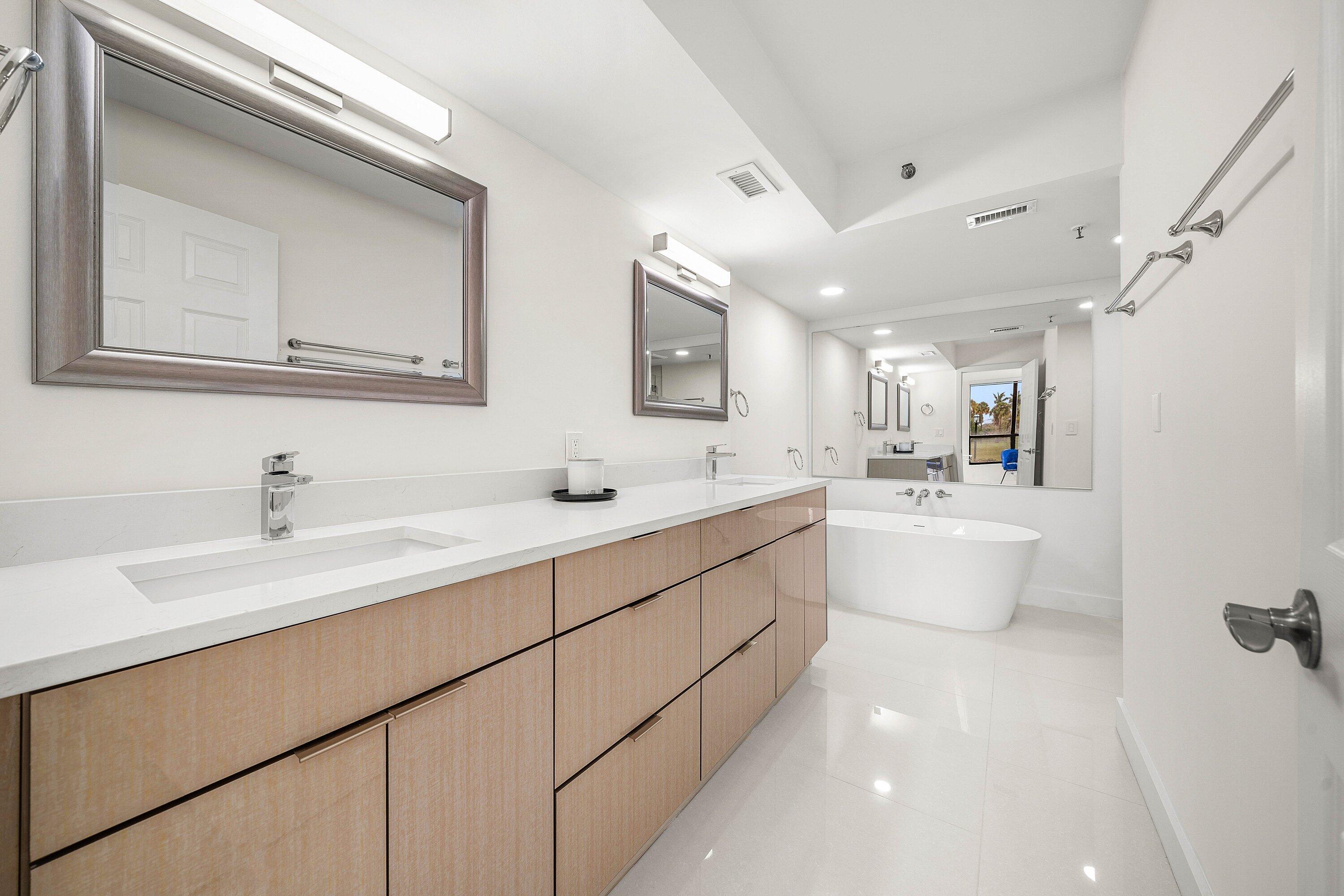 7145 Promenade Drive, Unit 101 Boca Raton, FL 33433 - Photo 21 of 35 a bathroom with a double vanity sink a mirror and a bathtub