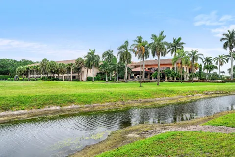 a view of a lake with a yard and palm trees