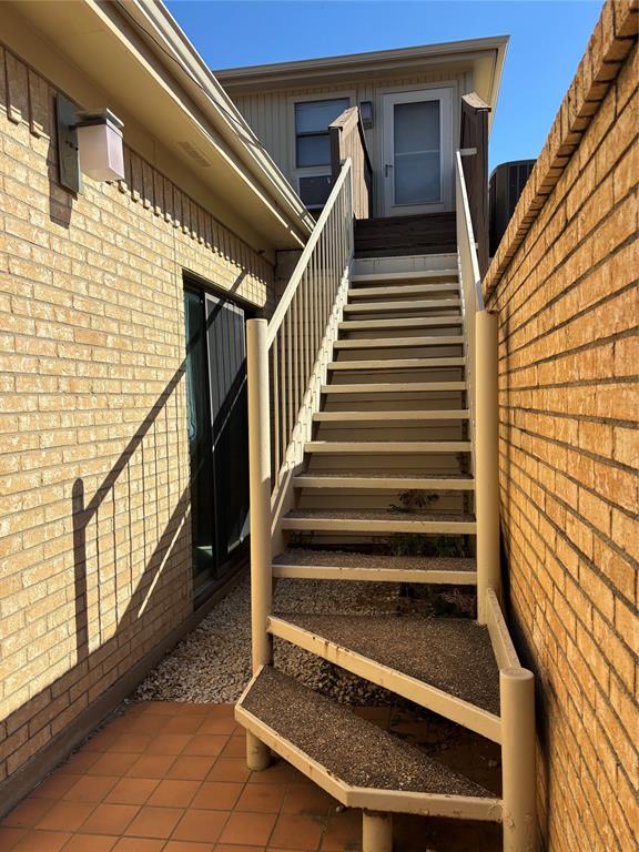 4702 Ranch View Road Fort Worth, TX 76109 - Photo 35 of 40 Exterior staircase with metal railings, brick wall, and terracotta tile patio
