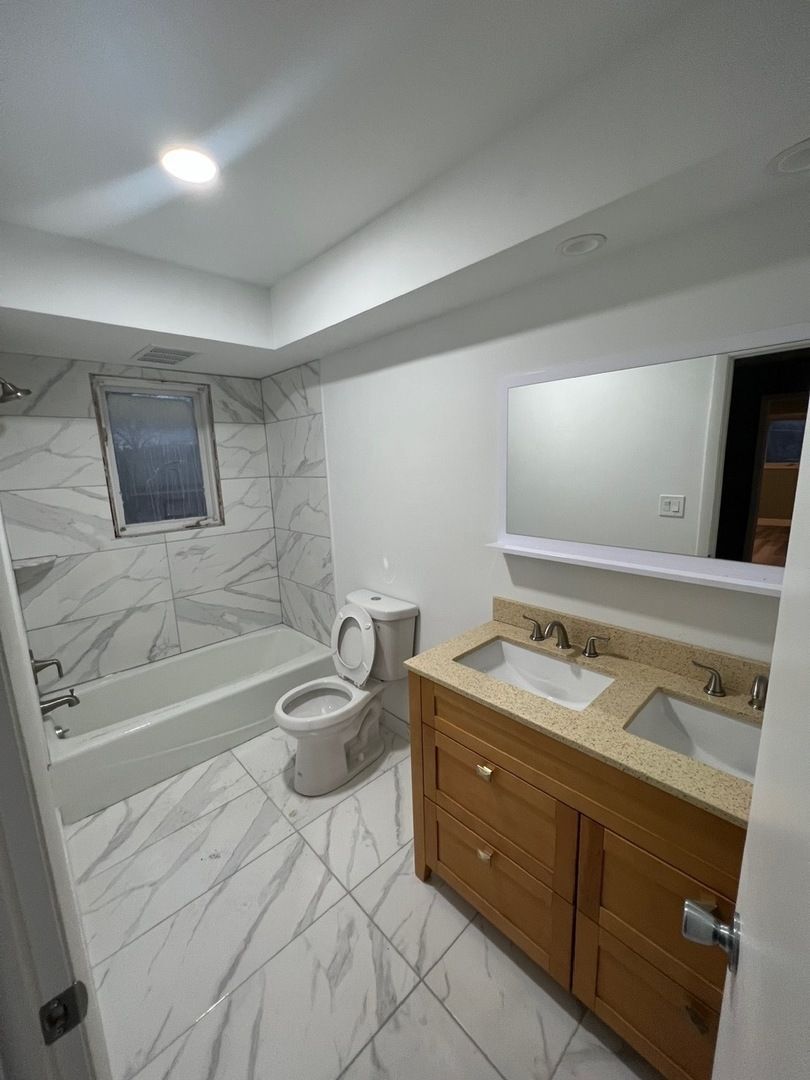 1631 Dundee Road Northbrook, IL 60062 - Photo 15 of 20 a bathroom with a granite countertop sink a toilet a mirror and bathtub