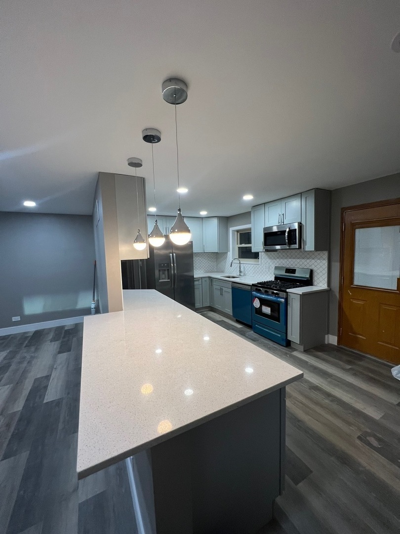 1631 Dundee Road Northbrook, IL 60062 - Photo 6 of 20 a large kitchen with stainless steel appliances a large counter top a stove and a refrigerator