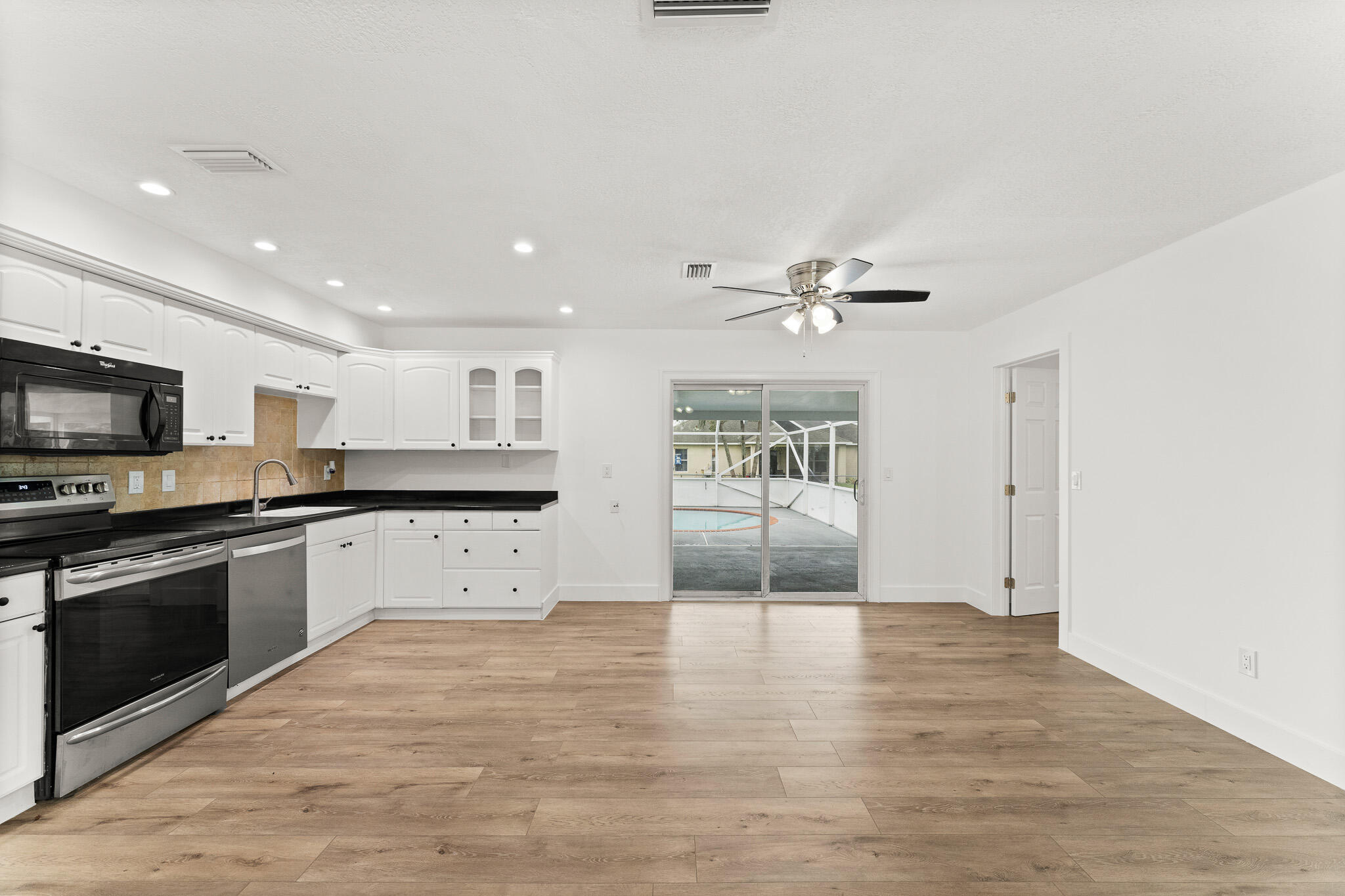 1575 Southwest Fresno Road Port St. Lucie, FL 34953 - Photo 12 of 27 a kitchen with stainless steel appliances granite countertop a stove top oven a sink dishwasher and a refrigerator with wooden floor