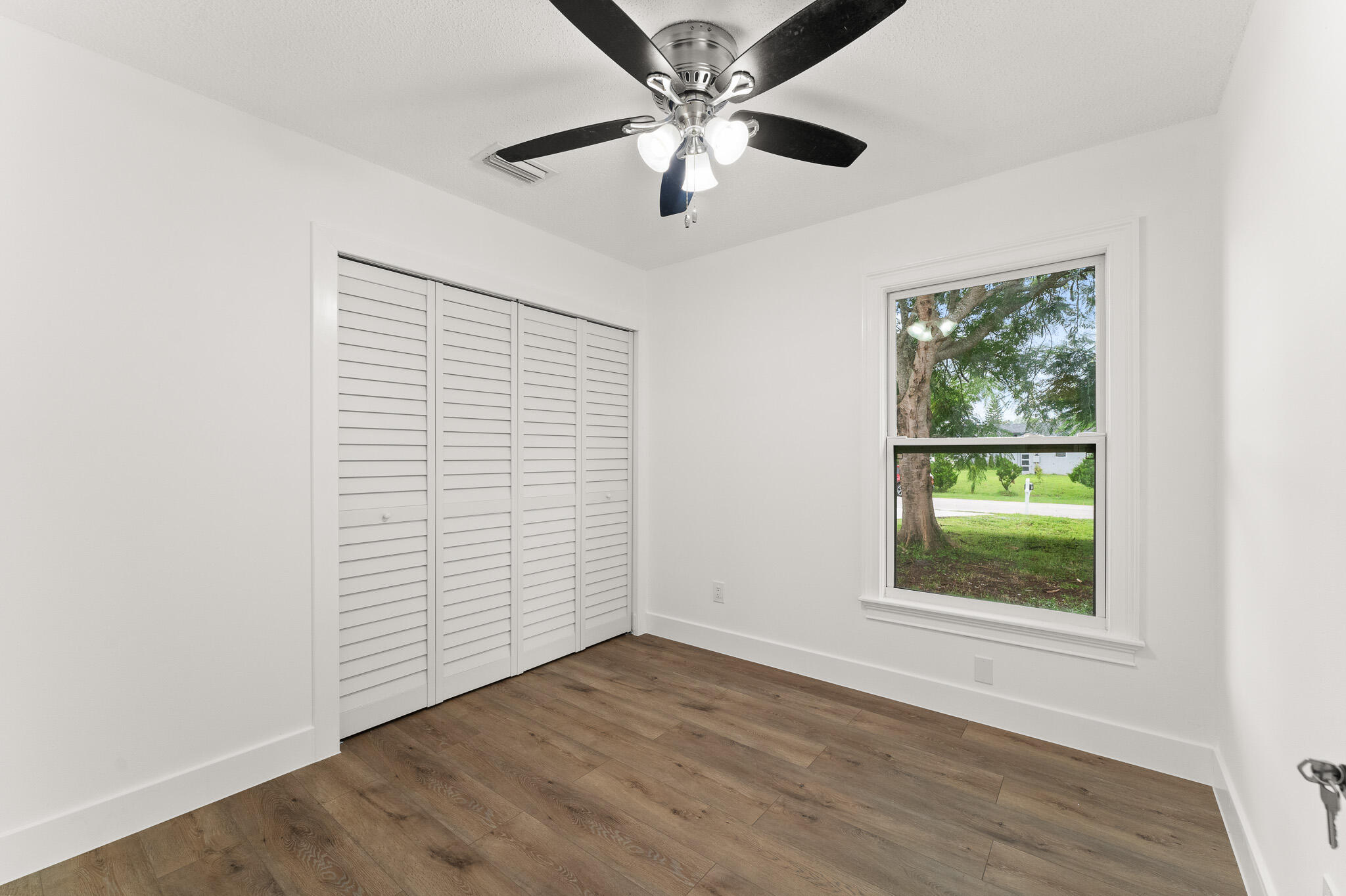 1575 Southwest Fresno Road Port St. Lucie, FL 34953 - Photo 18 of 27 an empty room with wooden floor chandelier fan and windows