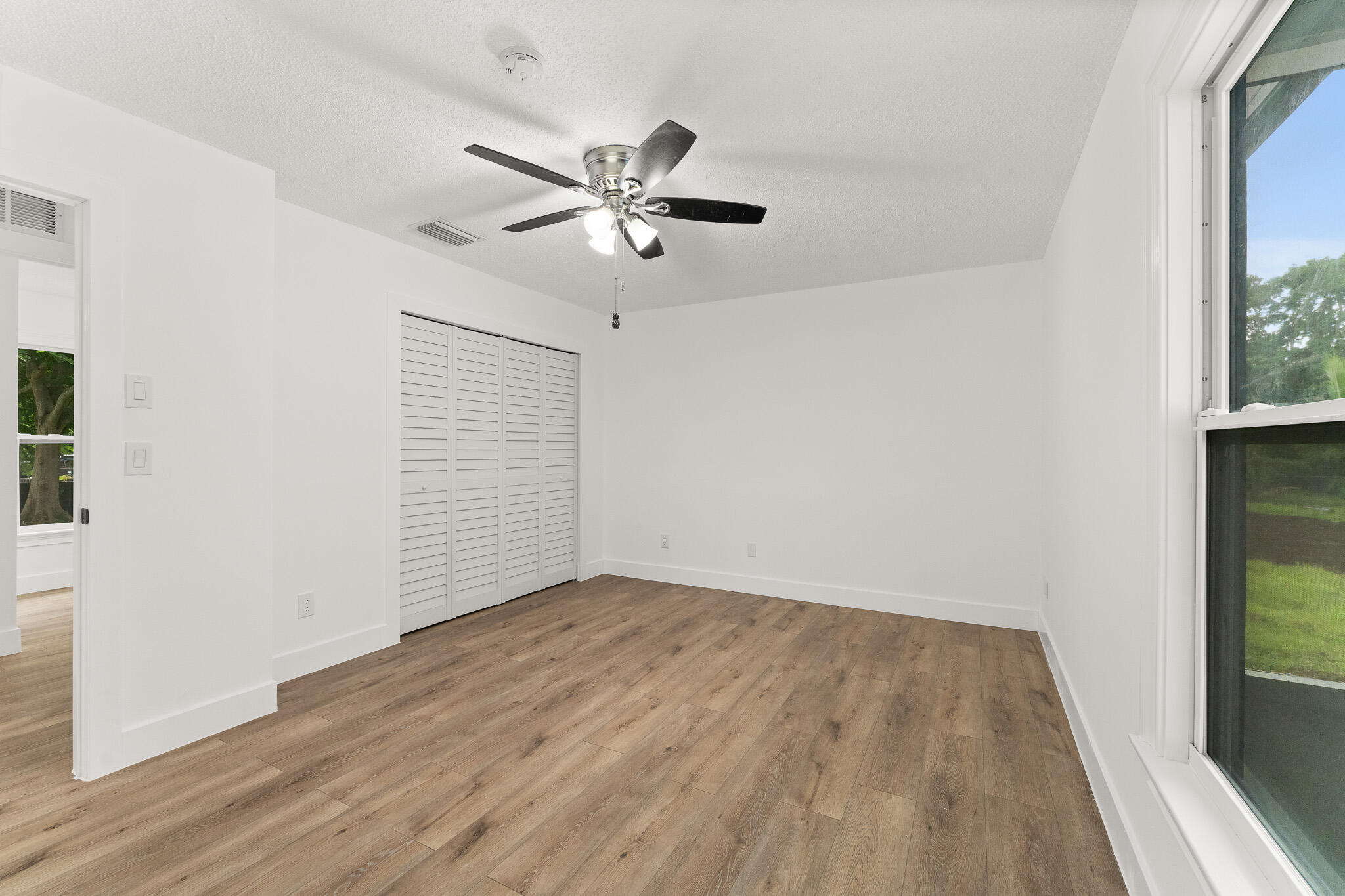 1575 Southwest Fresno Road Port St. Lucie, FL 34953 - Photo 20 of 27 an empty room with wooden floor fan and windows