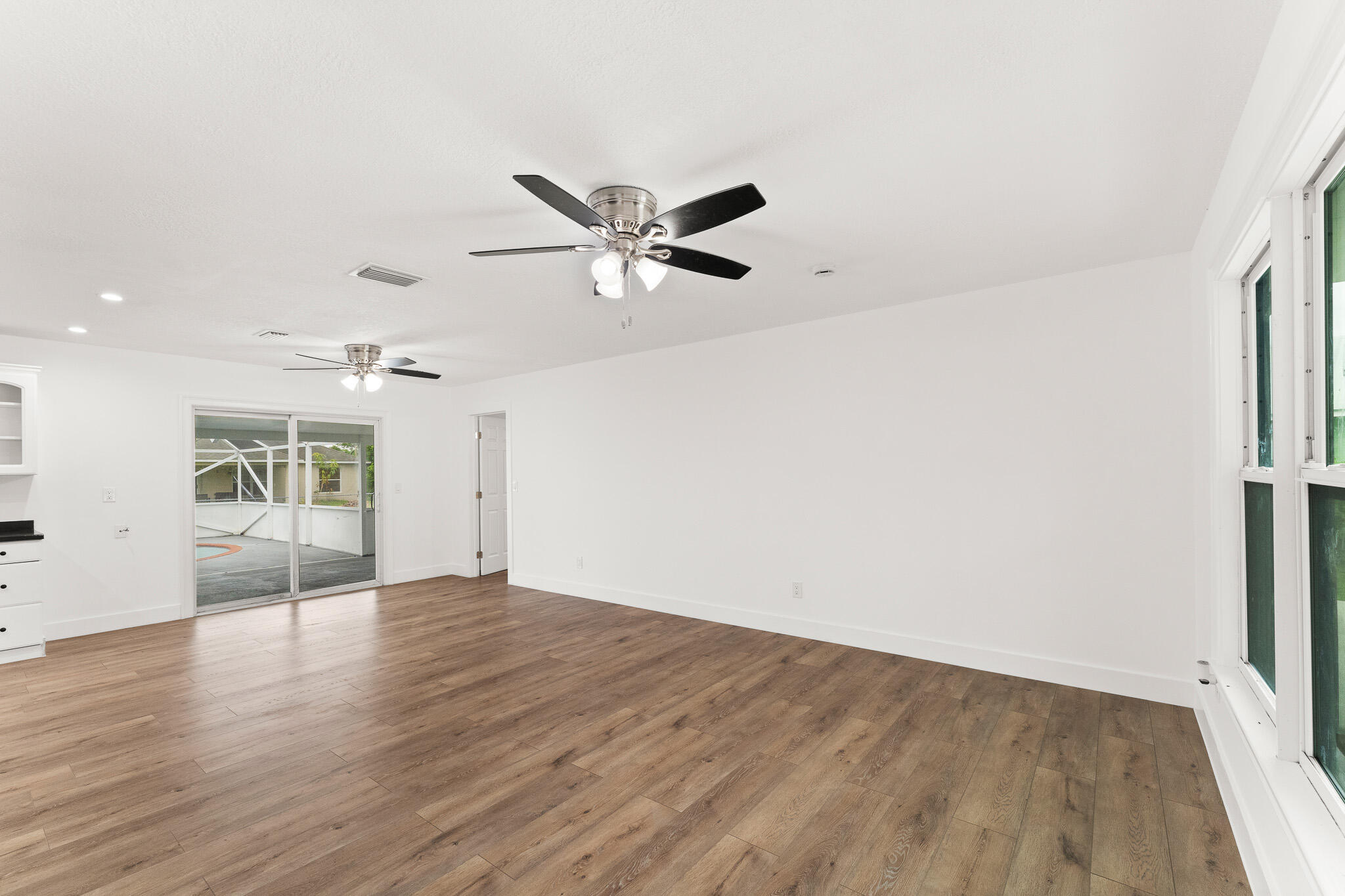 1575 Southwest Fresno Road Port St. Lucie, FL 34953 - Photo 9 of 27 an empty room with wooden floor and ceiling fan