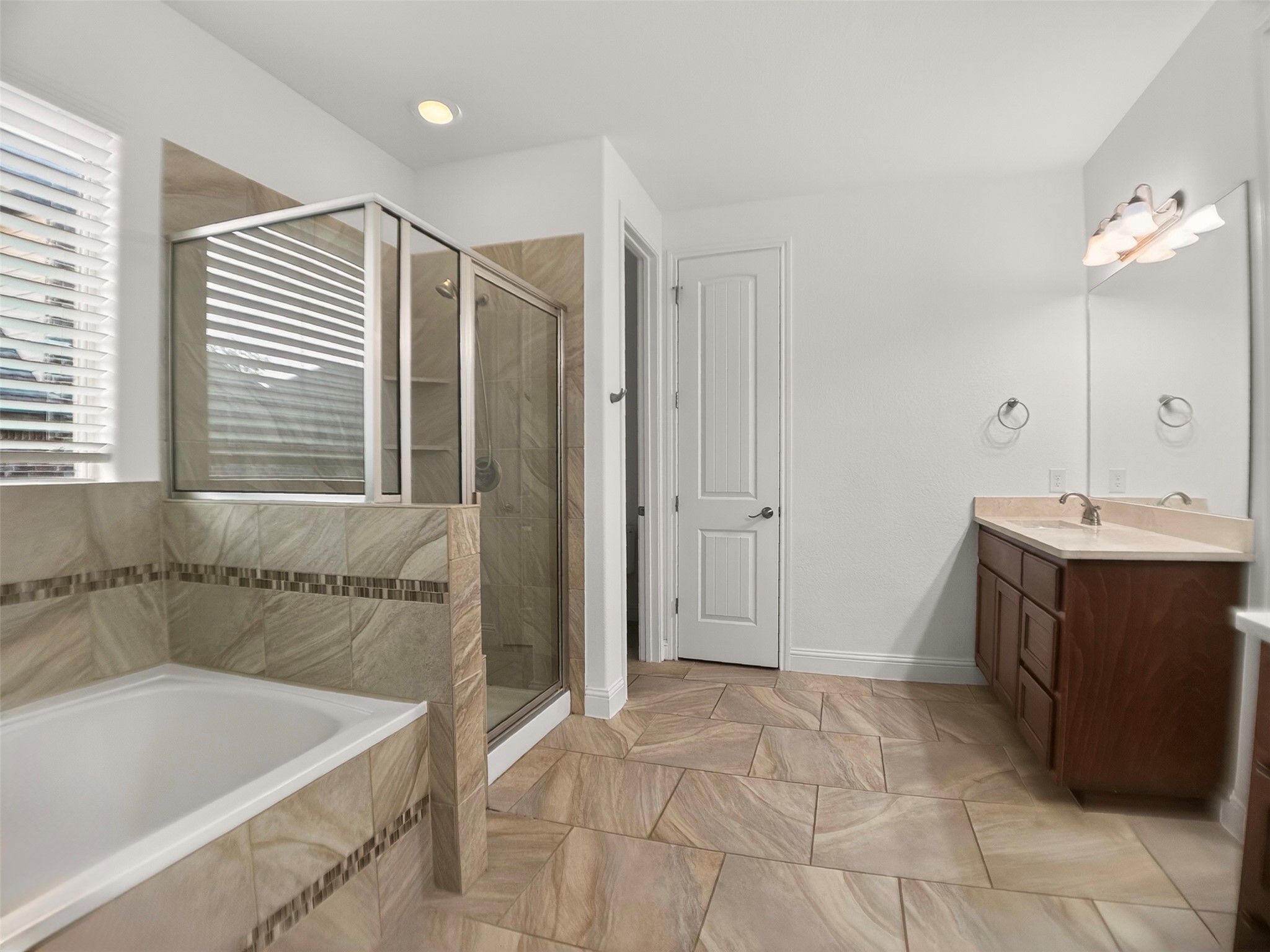 1505 Long Shadow Lane Georgetown, TX 78628 - Photo 15 of 28 Bathroom featuring a tiled soaking tub, glass-enclosed shower, dual vanity with a light countertop, and expansive floor tiling