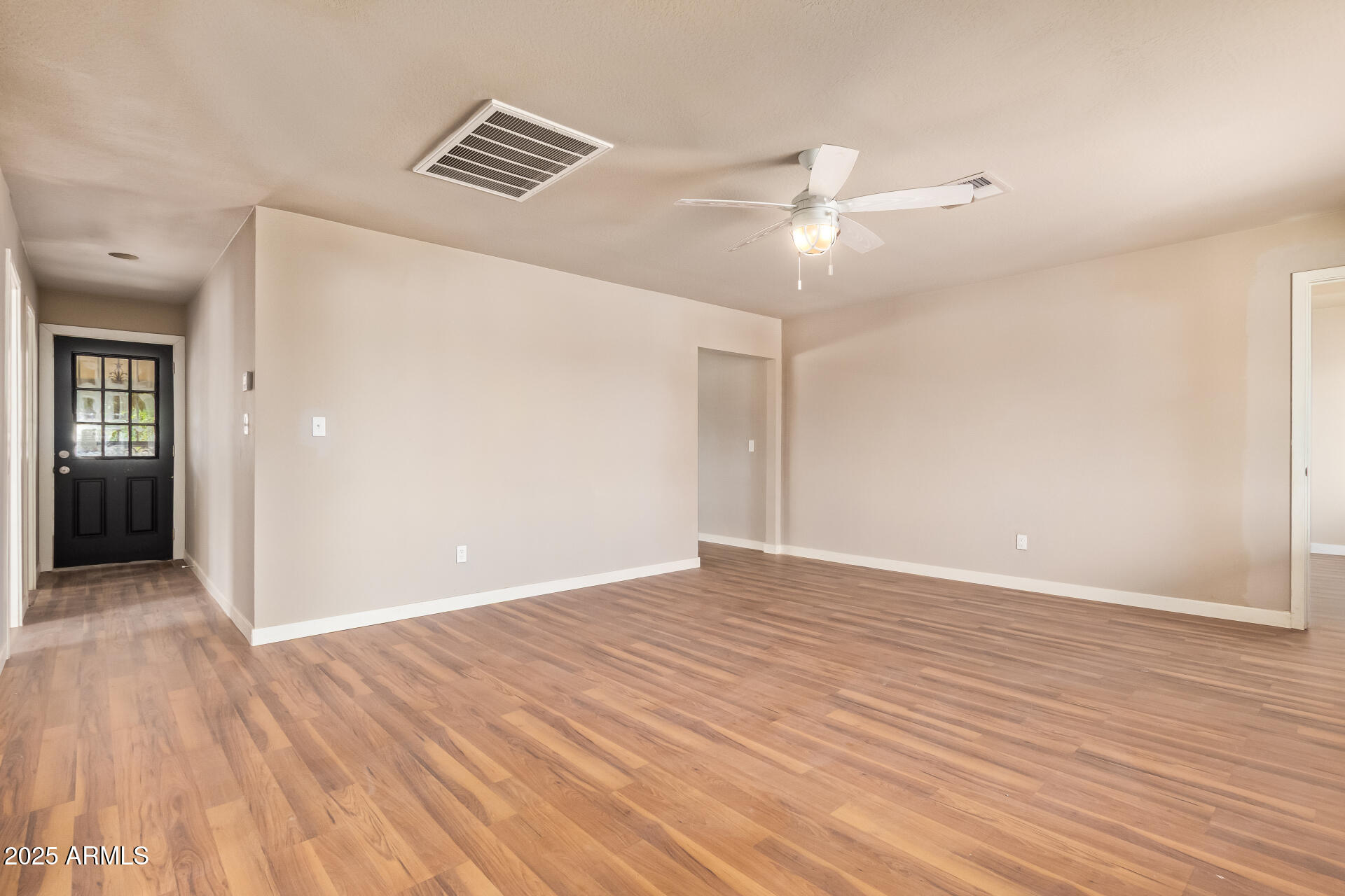 3527 West Almeria Road Phoenix, AZ 85009 - Photo 11 of 32 a view of an empty room with wooden floor and a ceiling fan