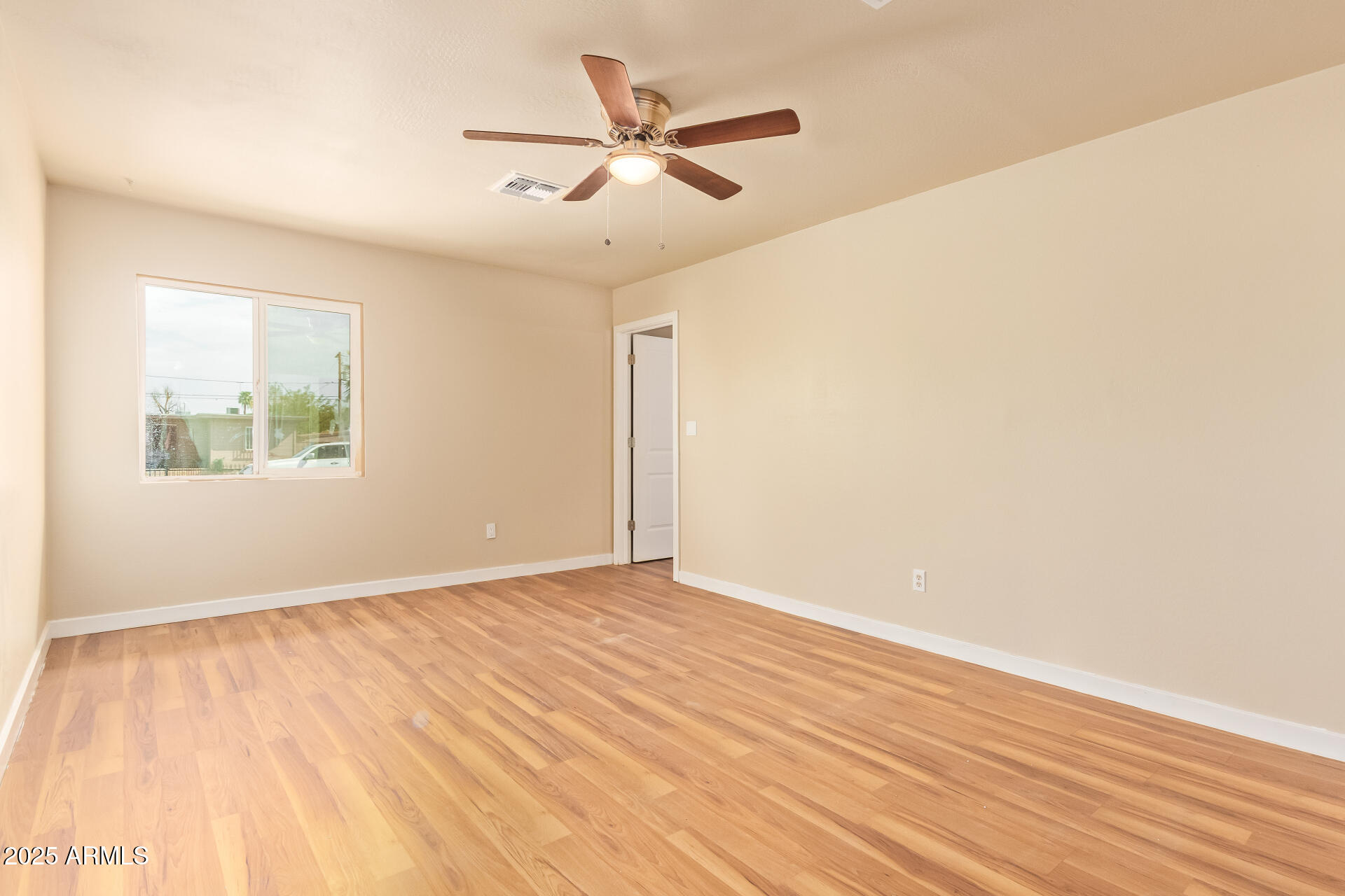 3527 West Almeria Road Phoenix, AZ 85009 - Photo 19 of 32 an empty room with wooden floor fan and windows