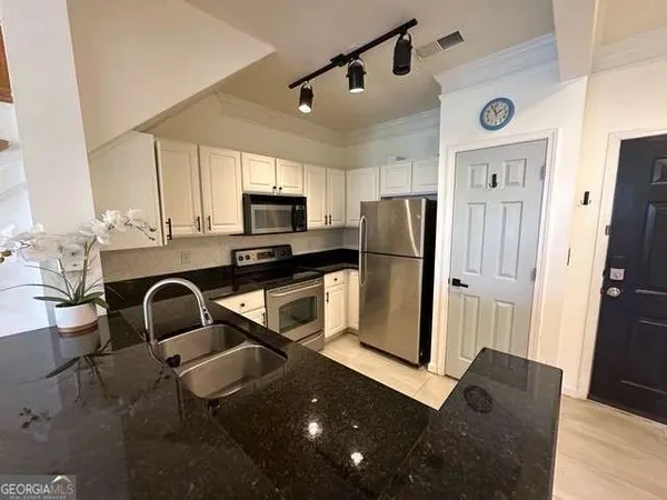 a kitchen with stainless steel appliances granite countertop a refrigerator a microwave a sink and wooden floor