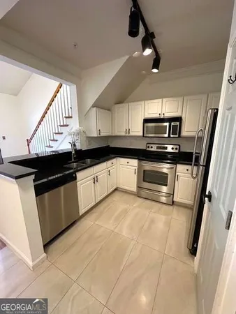 a kitchen with stainless steel appliances granite countertop a sink a stove top oven a chimney and a granite counter top