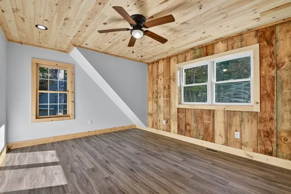 a view of an empty room with a window and wooden floor