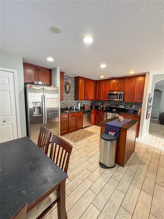 12715 Saulston Place Hudson, FL 34669 - Photo 14 of 44 a kitchen with stainless steel appliances kitchen island granite countertop a stove a refrigerator a sink a dining table and chairs